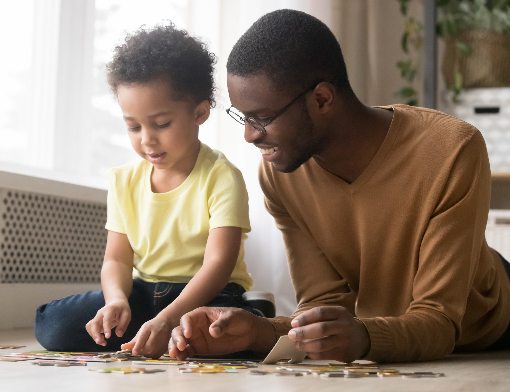 Pai e filho montando quebra cabeça no chão da sala