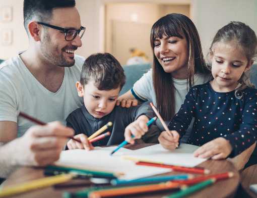 Pais com seus filhos ajudando eles a colorirem