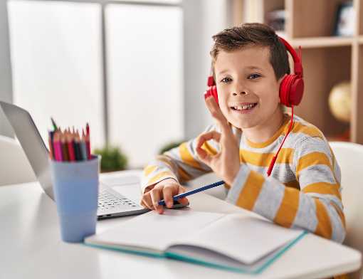 Menino estudando em casa com fones vermelhos